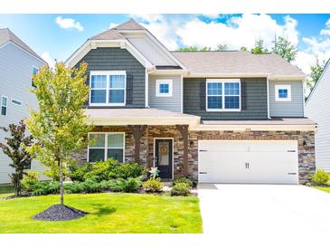 Charming two-story home featuring stone accents, a two-car garage, and a well-maintained lawn with mature tree at 334 Kennerly Center Dr, Mooresville, NC 28115