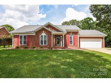 Charming brick home featuring red shutters, a well-manicured lawn, and a two-car garage at 4320 Atkinson Way, Monroe, NC 28110
