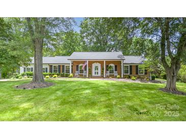 Charming brick home with inviting front porch, rocking chairs, and beautifully landscaped front yard at 441 Crestside Se Dr, Concord, NC 28025