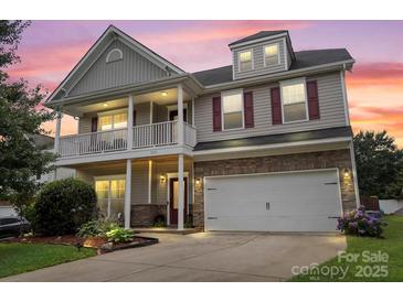 Inviting two-story home featuring a charming front porch, stone accents, and a well-manicured lawn at 5111 Elementary View Dr, Charlotte, NC 28269