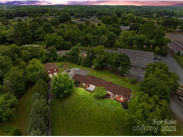 Expansive property featuring a brick home, additional brick building, and a barn surrounded by lush greenery at 10637 Highway 52 Hwy, Rockwell, NC 28138
