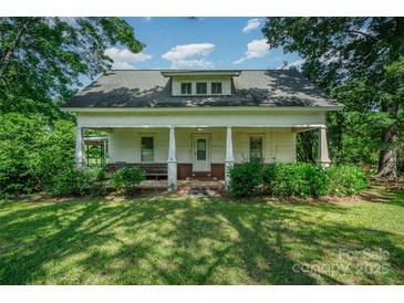 Charming single-story home featuring a covered front porch with white pillars, surrounded by mature trees and a lush green lawn at 4612 Rehobeth Rd, Waxhaw, NC 28173
