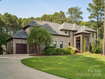 Stately brick home with a well-manicured lawn, mature trees, and a curved driveway leading to a two-car garage at 172 Barber Loop, Mooresville, NC 28117