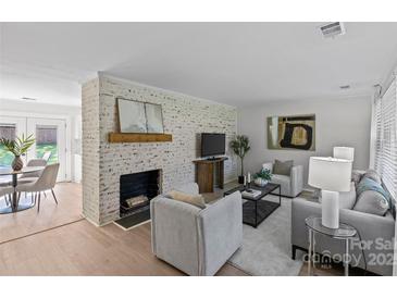 Bright living room featuring a brick fireplace, light wood floors, and neutral-toned furnishings at 5329 Valley Forge Rd, Charlotte, NC 28210