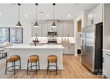Bright kitchen features a large island with seating, stainless steel appliances, and grey cabinets at 223 Halemarg Dr, Belmont, NC 28012