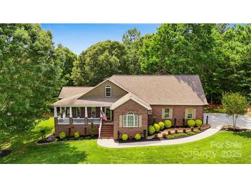Charming brick home featuring a landscaped front yard, covered porch, and well-manicured shrubbery at 234 Rivercliff Dr, Stony Point, NC 28678