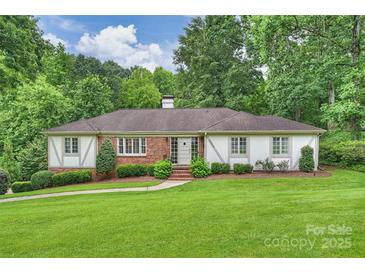 Charming single-story home with a brick and white facade, lush lawn, and mature trees providing privacy at 3504 Mountainbrook Rd, Charlotte, NC 28210
