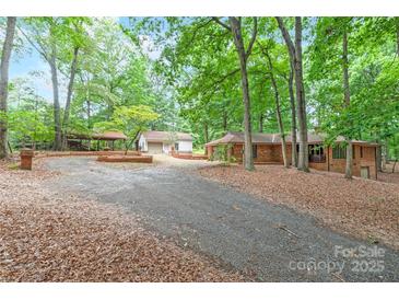 Charming brick home with a long driveway, lush trees, and a separate garage at 3985 Well Rd, Mint Hill, NC 28227