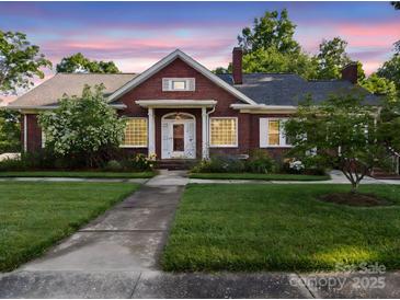 Charming brick home featuring manicured lawn, inviting front porch, and blossoming trees at 729 Montgomery Ave, Albemarle, NC 28001