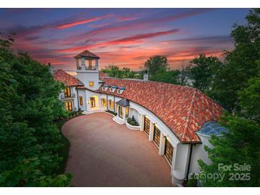 Stunning sunset view of a luxury estate featuring an elegant circular driveway and clay tile roof at 173 Rehoboth Ln, Mooresville, NC 28117