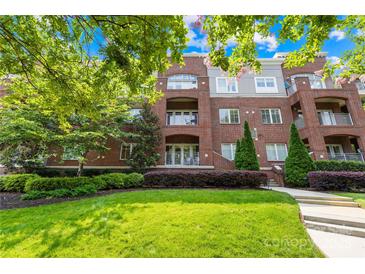 Beautiful brick condo building featuring manicured lawn, mature landscaping, and private balconies at 1903 Kenilworth Ave # 104A, Charlotte, NC 28203