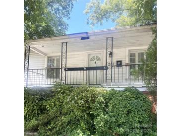 Inviting front porch featuring a decorative railing and white siding, complemented by lush greenery at 237 Institute St, Mooresville, NC 28115