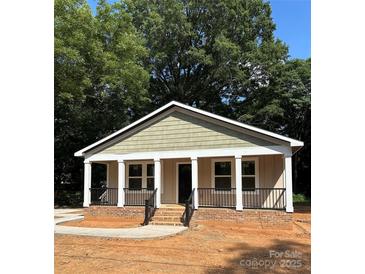 Charming single-story home with a welcoming porch and well-manicured landscaping at 307 Wilson St, Monroe, NC 28112