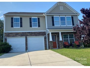 Charming two-story home features a two-car garage, stone accents, and a cozy front porch seating area at 4151 Granite St, Midland, NC 28107