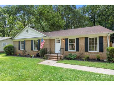 Charming brick home featuring a well-manicured lawn, black shutters, and an American flag at 6215 Cross Creek Ln, Charlotte, NC 28212