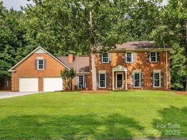 Charming two-story brick home with attached garage and mature trees on a lush green lawn at 113 Foxfield Ln, Matthews, NC 28105