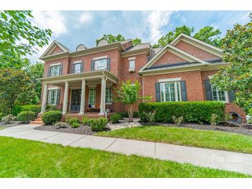 Charming brick home featuring a covered front porch with white columns and professionally landscaped yard at 2004 Viscount Dr, Matthews, NC 28104