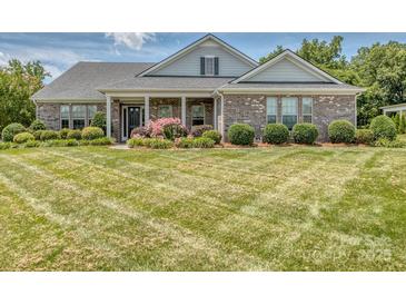 Charming brick home featuring manicured landscaping and a well-maintained, expansive front lawn at 314 Candella Dr, Matthews, NC 28104