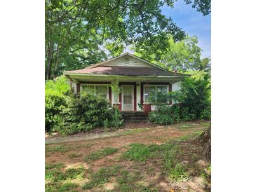 Charming red and white exterior with a covered porch surrounded by lush greenery at 423 Tot Dellinger Rd, Cherryville, NC 28021