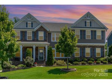 Charming two-story home boasting a landscaped yard, stone accents, and welcoming front porch at 4386 Oldstone Dr, Harrisburg, NC 28075