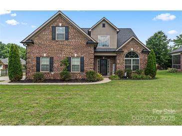 Charming brick home features a well-manicured lawn and lovely landscaping with mature trees and bushes at 5379 Roberta Meadows Ct, Concord, NC 28027