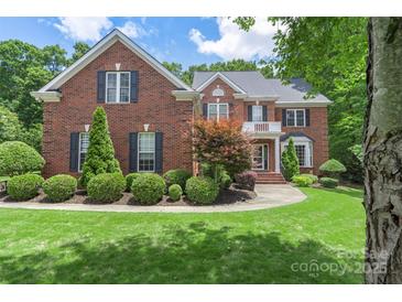 Beautiful two-story red brick home featuring a manicured lawn, mature trees, and classic architectural details at 6006 Casswell Cir, Matthews, NC 28104