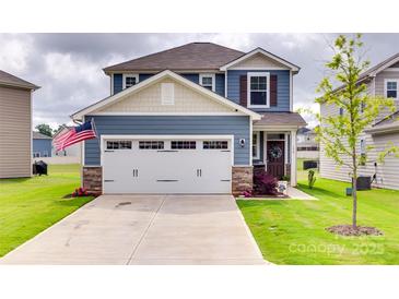 Charming two-story home with a two car garage, stone accents, landscaped lawn, and an American flag at 150 Bezelle Ave, York, SC 29745