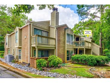 Multi-level condo with brick and siding exterior, surrounded by lush trees and landscaping at 1606 Sharon W Rd # 40, Charlotte, NC 28210