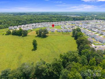 Expansive aerial view of a suburban neighborhood, showcasing a spacious green field and well-maintained homes at 117 Carmine Ct, Troutman, NC 28166