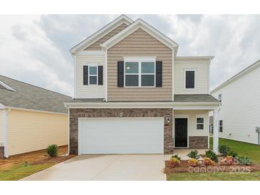 Two-story home features a two-car garage, stone accents, neutral siding, and a well manicured lawn at 1266 Langston Ln, Salisbury, NC 28144