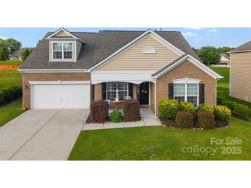 Charming brick home with a manicured lawn, attached garage, and inviting front porch and well landscaped beds at 163 Sassafras Rd, Mooresville, NC 28115
