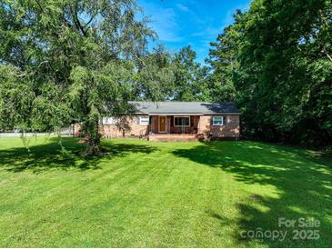 Charming single-story brick home with a lush green lawn and mature trees at 12143 Asbury Chapel Rd, Huntersville, NC 28078