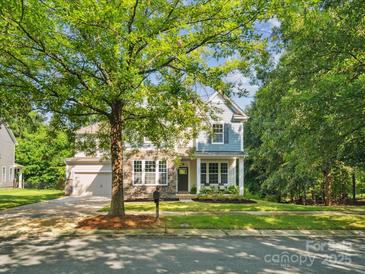 Charming two-story home with stone accents, a well-manicured lawn, and mature trees offering plenty of shade at 1008 Millbridge Pkwy, Waxhaw, NC 28173