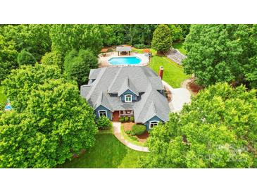 Beautiful home from above, showcasing a well-kept lawn, swimming pool, and mature landscaping at 1042 Heather Glen Dr, Matthews, NC 28104