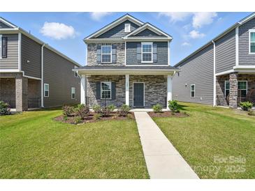 Charming two-story home with stone accents, gray shutters, well-maintained lawn and walkway at 125 Cedar Knoll Cir, Pineville, NC 28134