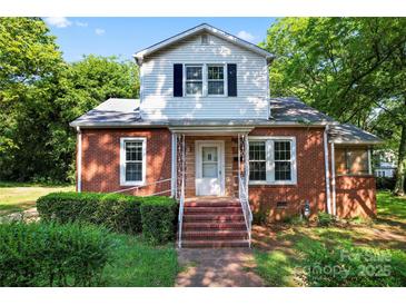 Charming brick home featuring a quaint front porch and mature landscaping at 317 Campus St, Charlotte, NC 28216