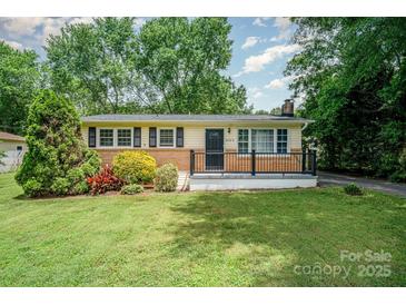Charming single-story home featuring lush landscaping and a welcoming front porch with black railing at 4720 Randleman Rd, Conover, NC 28613