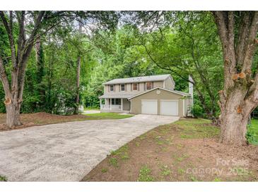 Charming two-story home featuring a two-car garage and a welcoming front porch nestled amongst mature trees at 7008 Wannamaker Ln, Charlotte, NC 28226