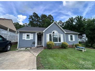 Charming one-story home with a well-manicured lawn, inviting entry and mature trees in the background at 7401 Merrily Ln, Charlotte, NC 28214