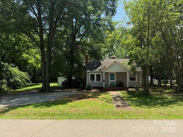 Charming one-story home with mature trees and inviting front porch, nestled in a serene, green landscape at 917 Tennyson Dr, Charlotte, NC 28208