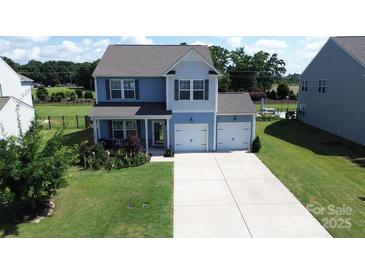 Two-story home with two-car garage, light blue siding, green grass, and well-maintained landscaping at 1019 Beacon Ave, Monroe, NC 28110