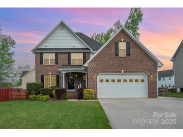 Charming two-story brick home featuring an attached two-car garage, well-manicured lawn, and a welcoming front garden at 1308 Stonewyck Dr, Salisbury, NC 28146