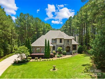 Beautiful stone and stucco home with lush landscaping and a circular driveway nestled among mature trees at 168 Blue Ridge Trl, Mooresville, NC 28117