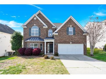 Charming two-story brick home with manicured lawn and attached two-car garage on a beautiful sunny day at 2275 Laurens Dr, Concord, NC 28027