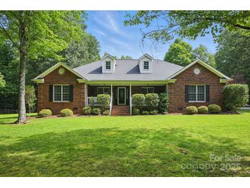 Charming brick home with well-manicured lawn and inviting front porch, complemented by lush green landscaping at 4824 Waxhaw Farms Rd, Waxhaw, NC 28173