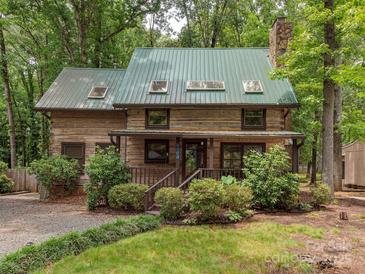 Charming log cabin featuring a metal roof, stone chimney, and cozy front porch at 5109 Walnut Grove Ln, Charlotte, NC 28227
