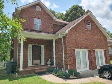 Charming brick home featuring a covered front porch, red shutters, and lush landscaping at 7318 Brighton Brook Dr, Charlotte, NC 28212