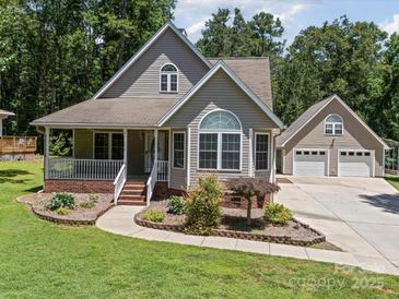 Charming two-story home featuring a welcoming front porch, beautiful landscaping, and a detached two-car garage at 179 Delwood Ct, Mount Gilead, NC 27371