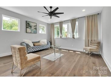 This living room features beautiful hardwood floors, a modern fan, and a comfortable couch at 1933 W Trade St, Charlotte, NC 28216