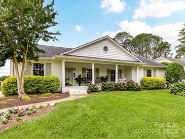 Charming single-story home with white painted brick, columns, and inviting front porch with beautiful landscaping at 2636 Chilton Pl, Charlotte, NC 28207